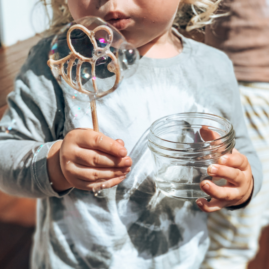 Young child with bee shaped bubble wand blowing bubbles. Australian made, all natural bubble wand which is biodegradable. Spark your childs imagination with nature toys.