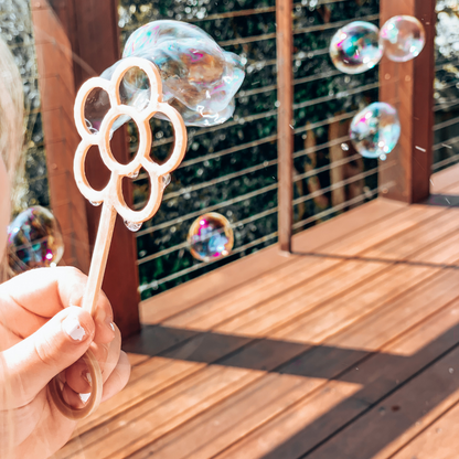 Young child with flower shaped bubble wand blowing bubbles. Australian made, all natural bubble wand which is biodegradable. Spark your child’s imagination with nature toys.